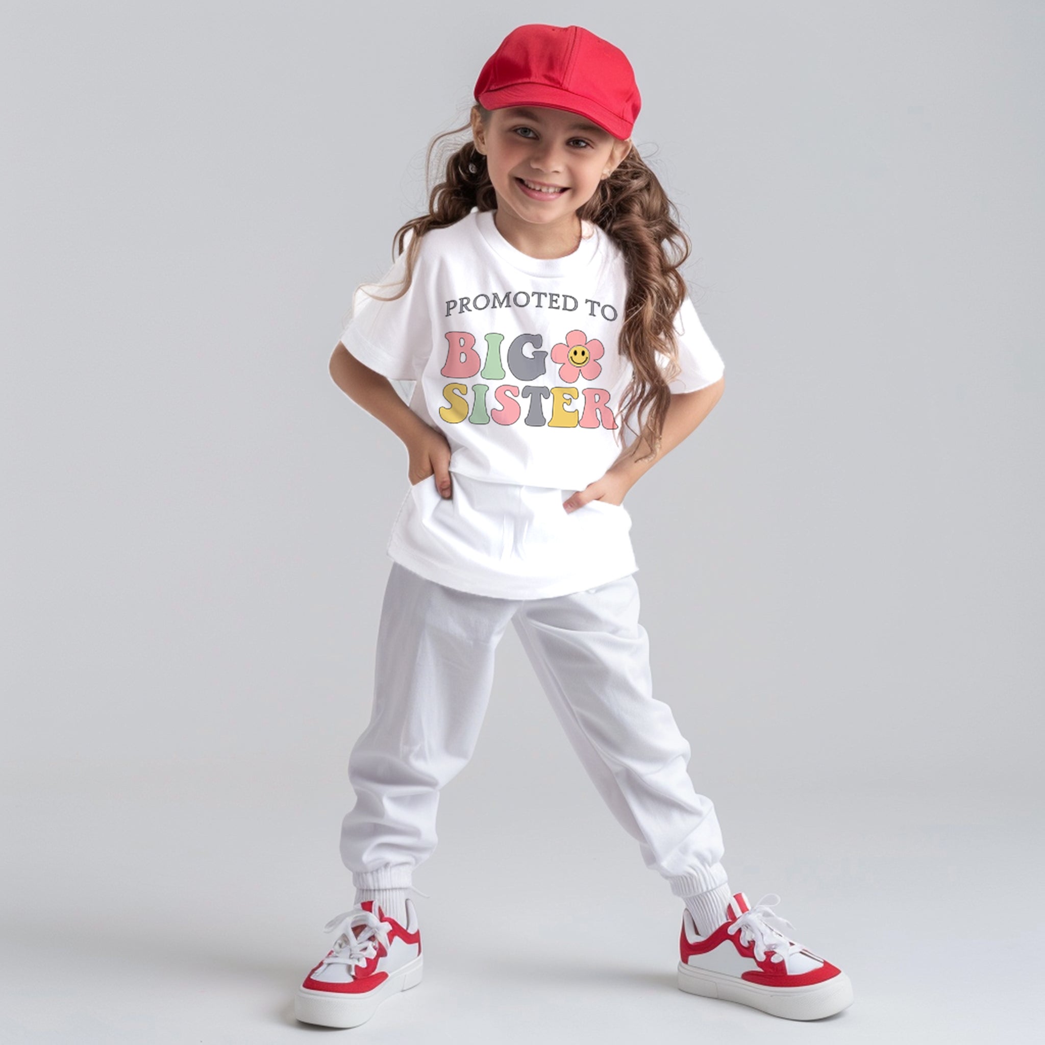 Trendy Tykes wearing a white t-shirt with a colorful design that reads "PROMOTED TO BIG SISTER" alongside playful flower illustrations.