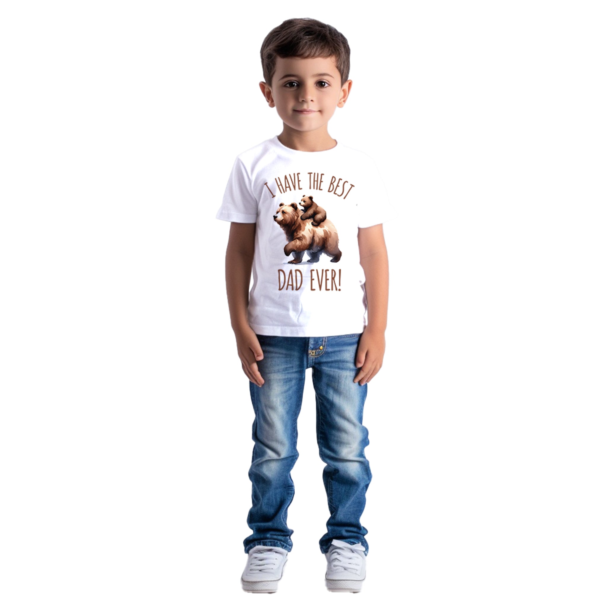 Trendy Tykes A young boy with short hair and a gentle smile stands against a white background. He is wearing a white T-shirt with the message 'I have the BEST DAD EVER!' featuring an illustration of two bears, paired with blue jeans and white sneakers.