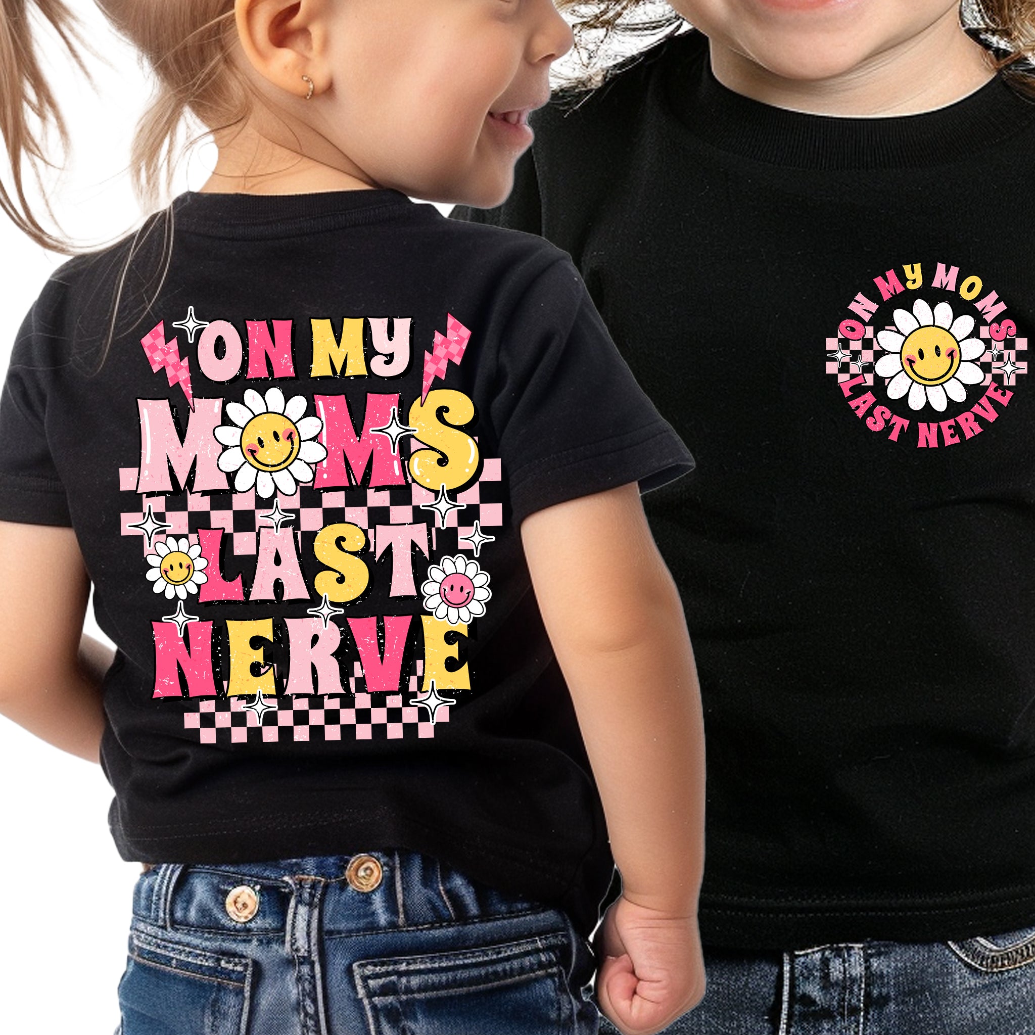 Trendy Tykes black t-shirt with a design saying 'On My Mom's Last Nerve' in vibrant pink, yellow, and checkerboard patterns, adorned with smiling suns, stars, and flowers.
