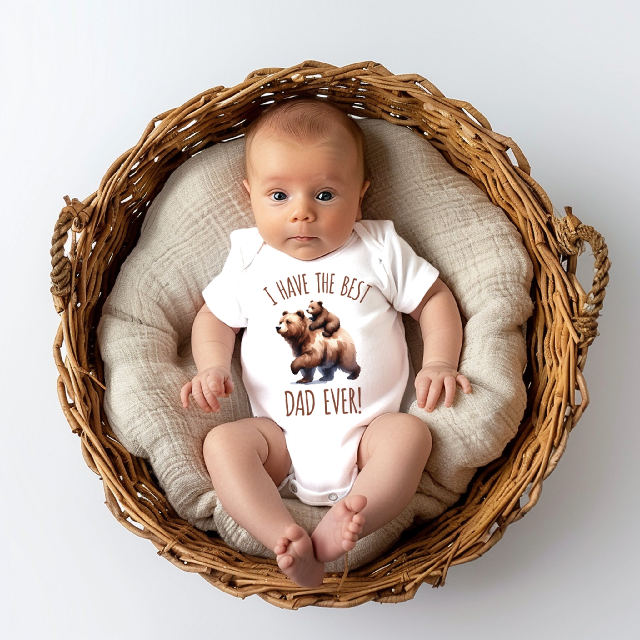 Trendy Tykes a baby in a onesie that reads "I have the best DAD ever!" with an adorable image of bears. This could be a popular item for those looking to celebrate fatherhood with a cute and heartwarming message. The basket setup is a nice touch for the photo too, v