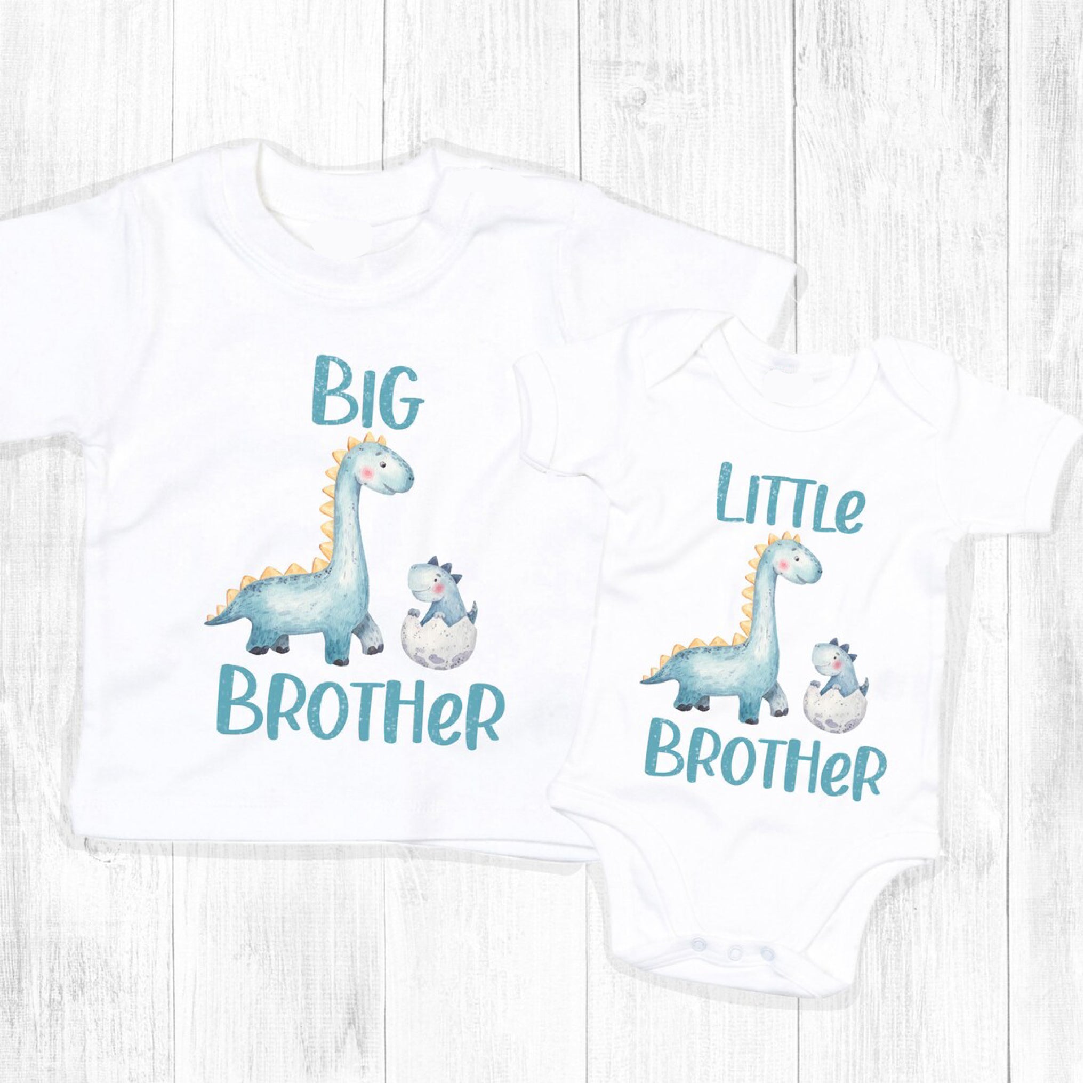 Trendy Tykes Big Brother Little Brother dinosaur matching outfit The image shows two white baby onesies with dinosaur designs, one saying "BIG BROTHER" and the other "LITTLE BROTHER,