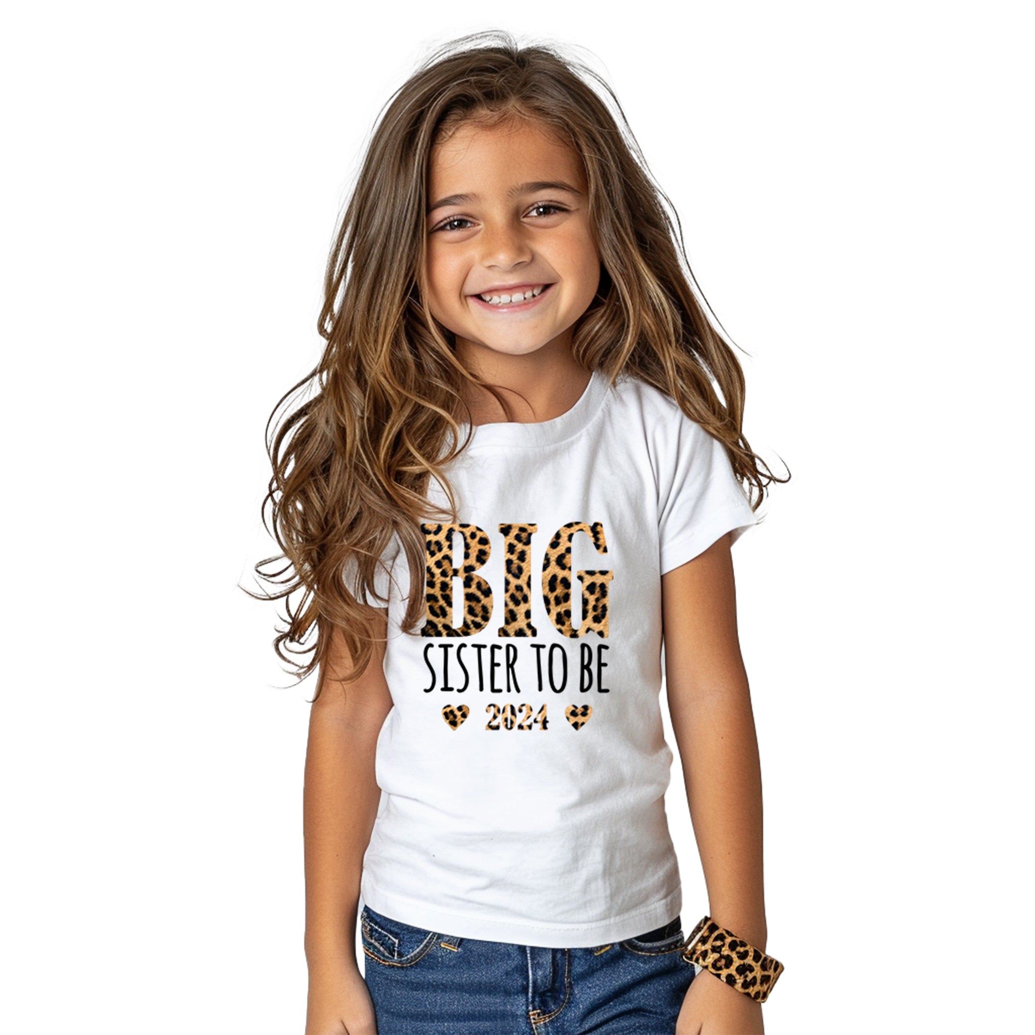 Smiling young girl wearing a Trendy Tykes white t-shirt with 'BIG SISTER TO BE' text in black and leopard print design, with hearts and the year '2024' printed below.